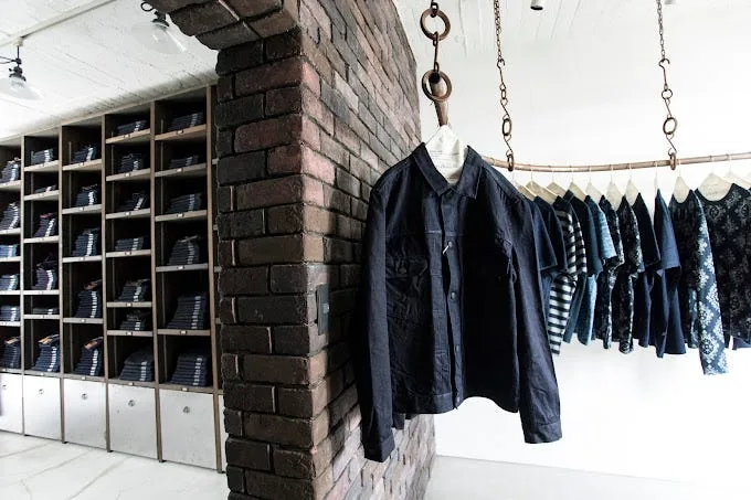 The interior of Pure Blue Japan in Harajuku, Tokyo, showing denim jackets, shirts, and a wall of denim jeans.