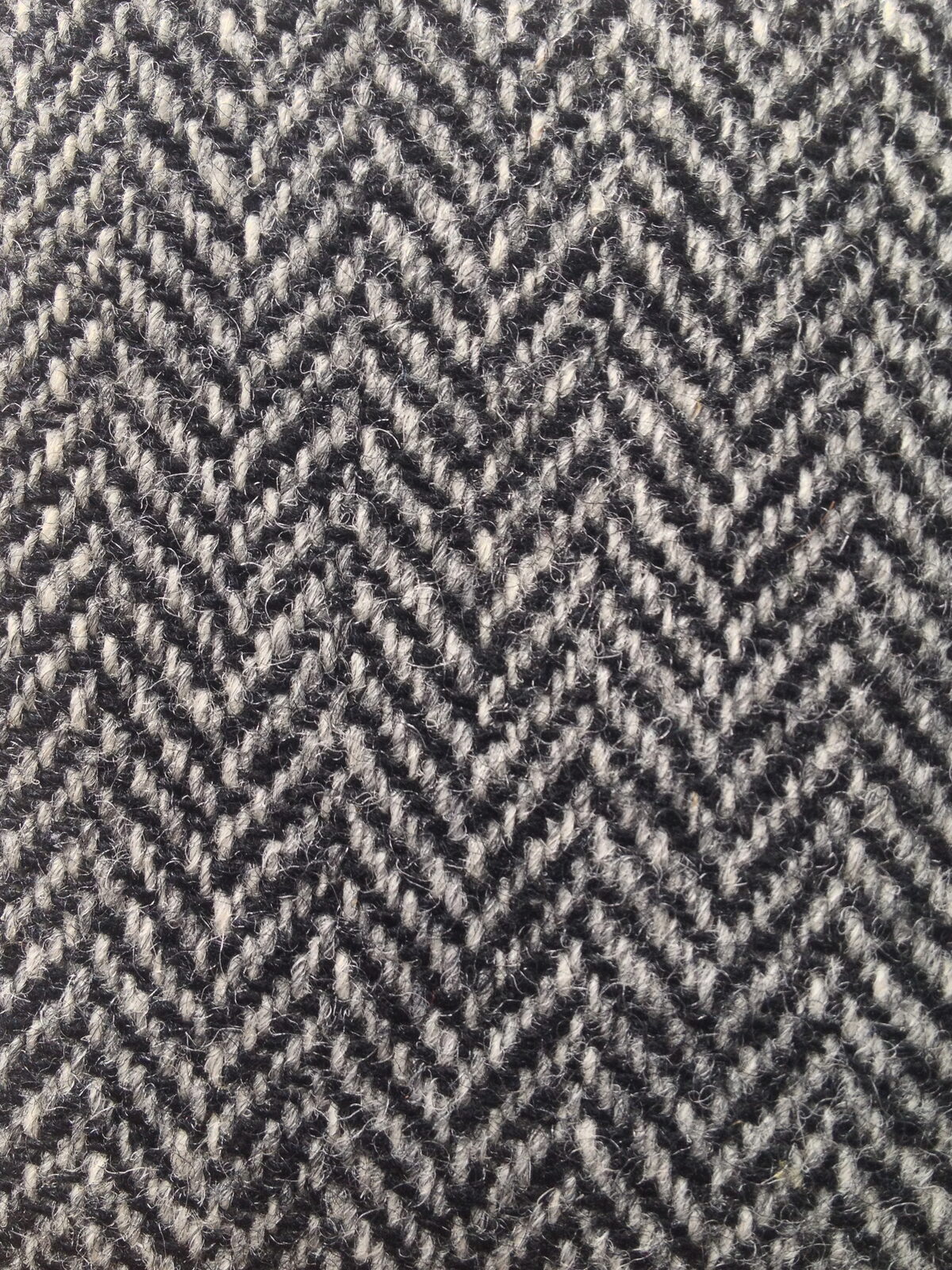 Close-up of a gray and white herringbone fabric with a repeating diagonal weave pattern.