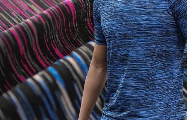 Person wearing a striped knit garment with alternating blue, black, and pink sections beside another striped textile.