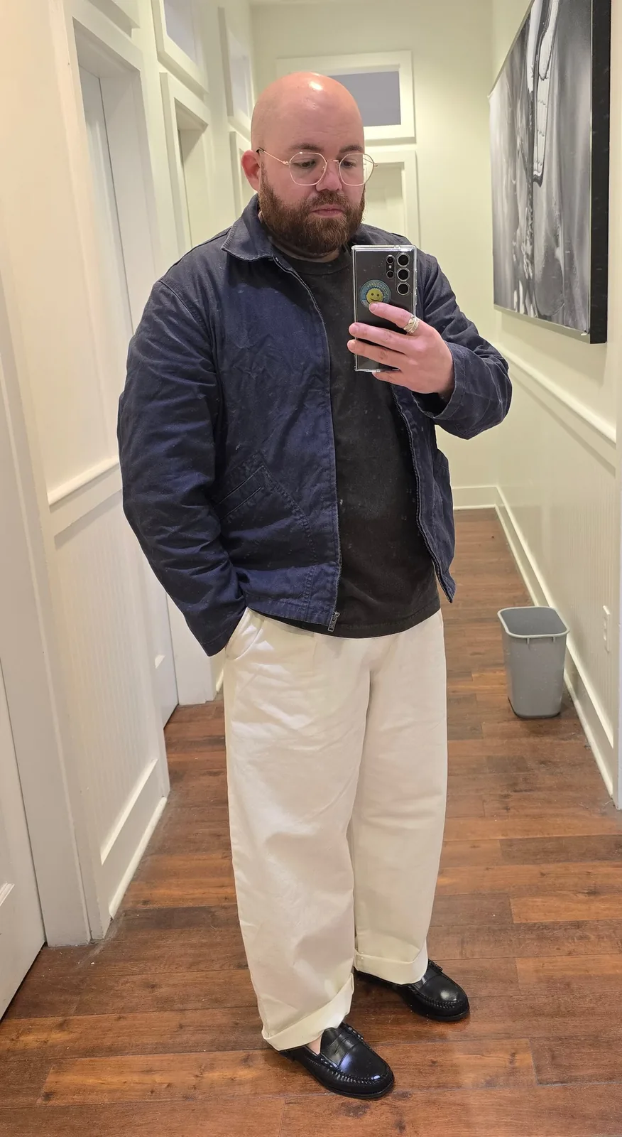 Chaz Stephens taking a mirror selfie in a hallway, wearing a navy Uniqlo x JW Anderson blouson jacket over a dark tee and off-white Uniqlo Barrel Pants with black J.Crew loafers.