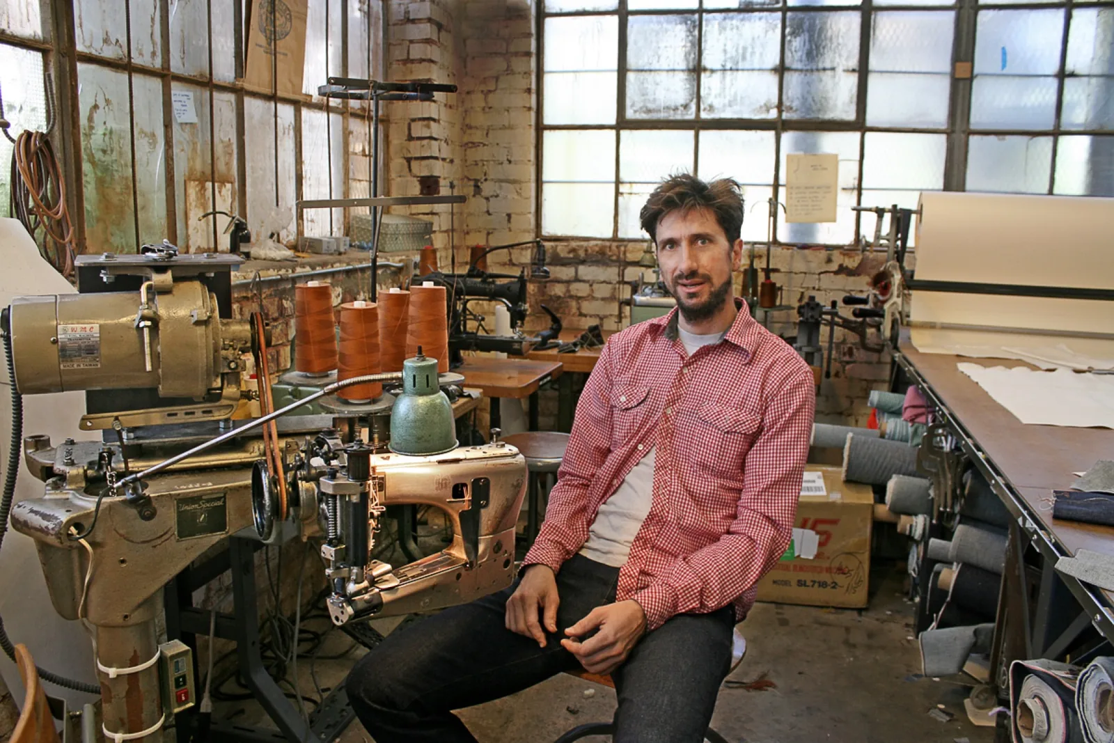 Roy Slaper seated among the sewing machines in his Oakland workshop