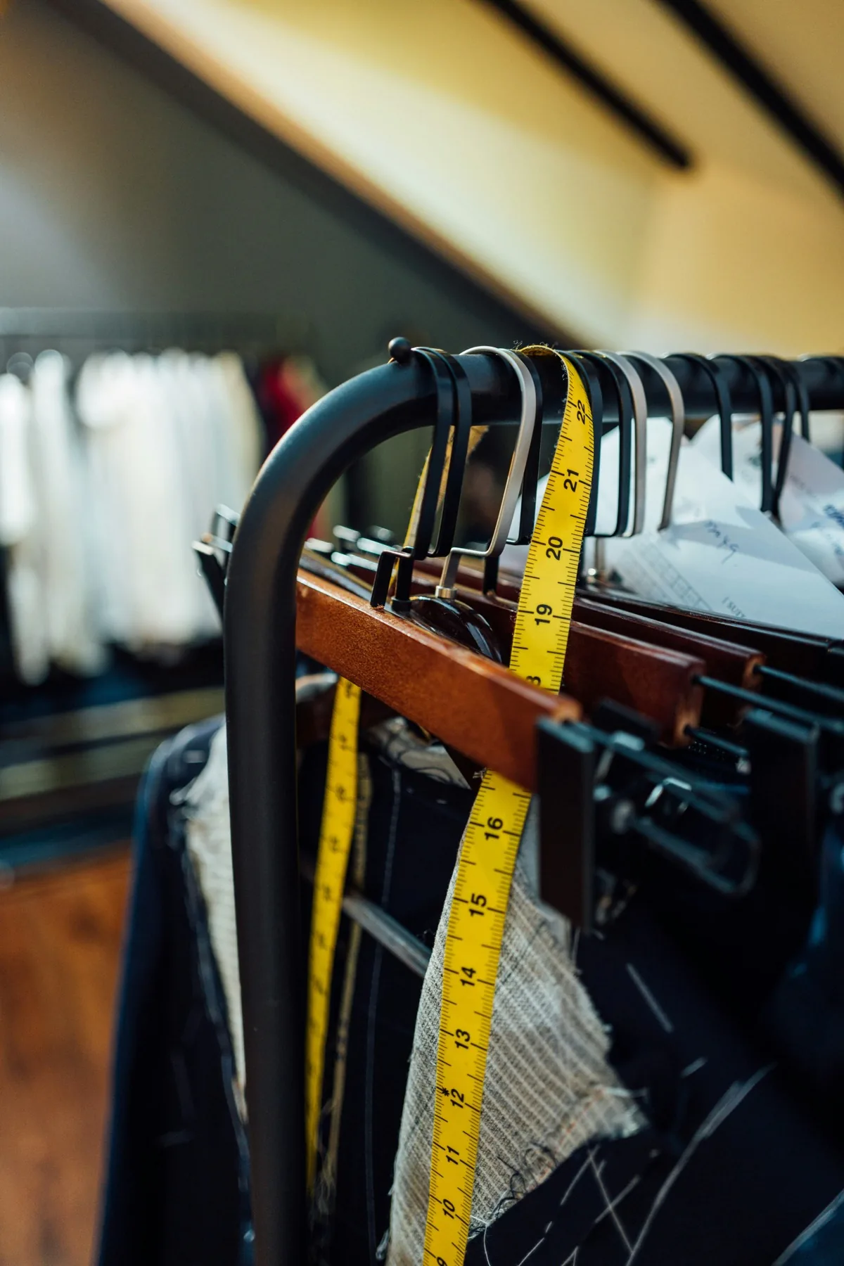 A rack of denim garments with a tape measure, illustrating the practice of measuring garments directly rather than trusting the size tag