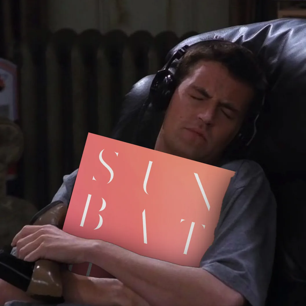 A man asleep in a recliner with headphones on, a pink-to-orange gradient card reading "SUNBATHER" propped in front of him.