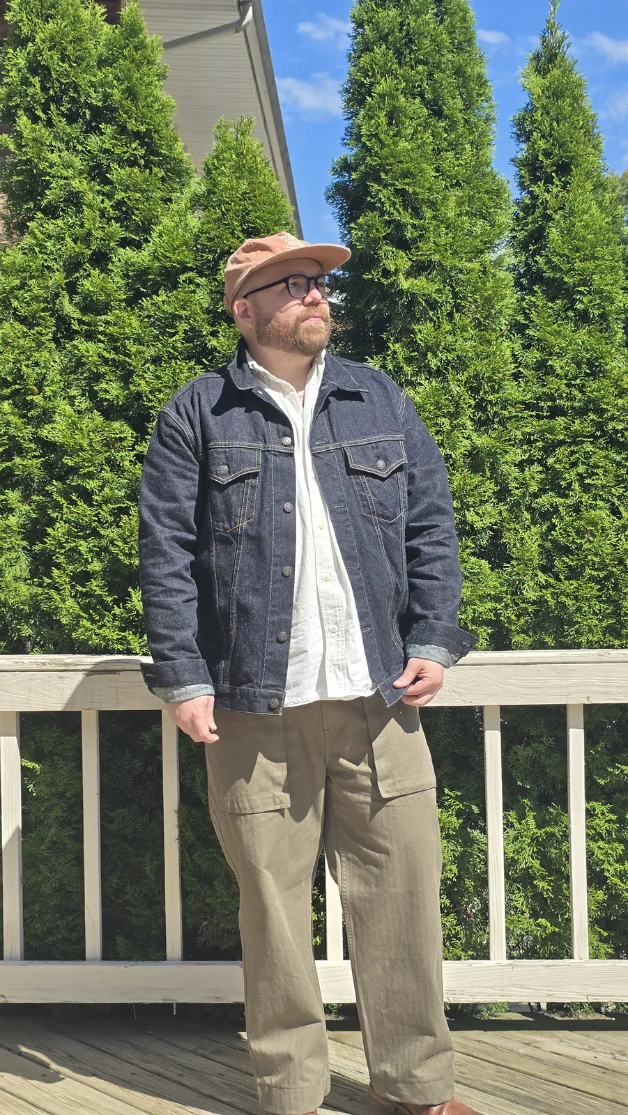 Chaz Stephens standing on a deck wearing a Flat Head Type 3 denim jacket over a white shirt with khaki trousers.